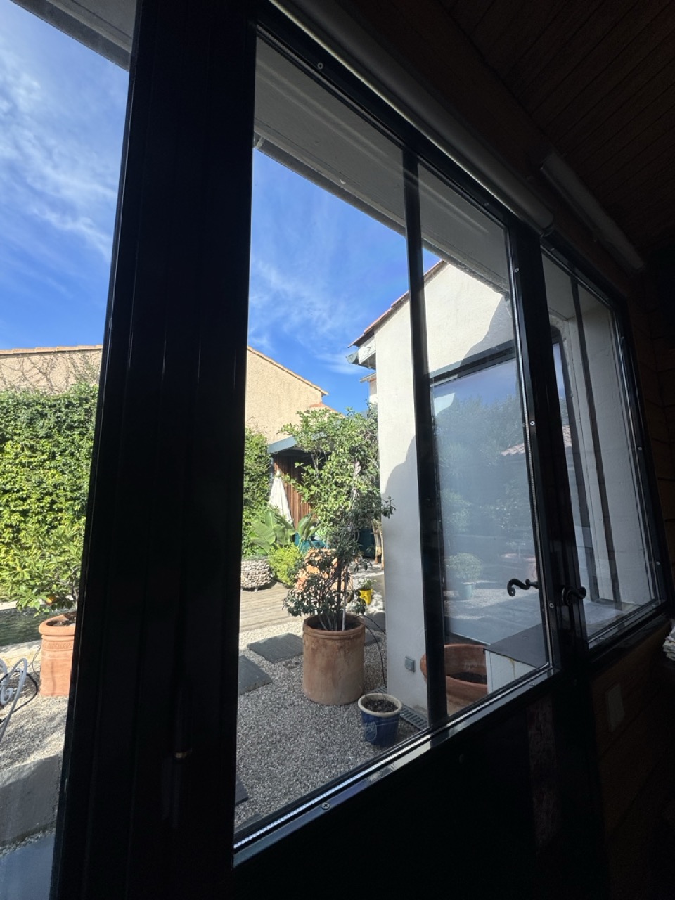 Vue rapprochée depuis l’intérieur du bureau : jardin visible à travers le film solaire transparent